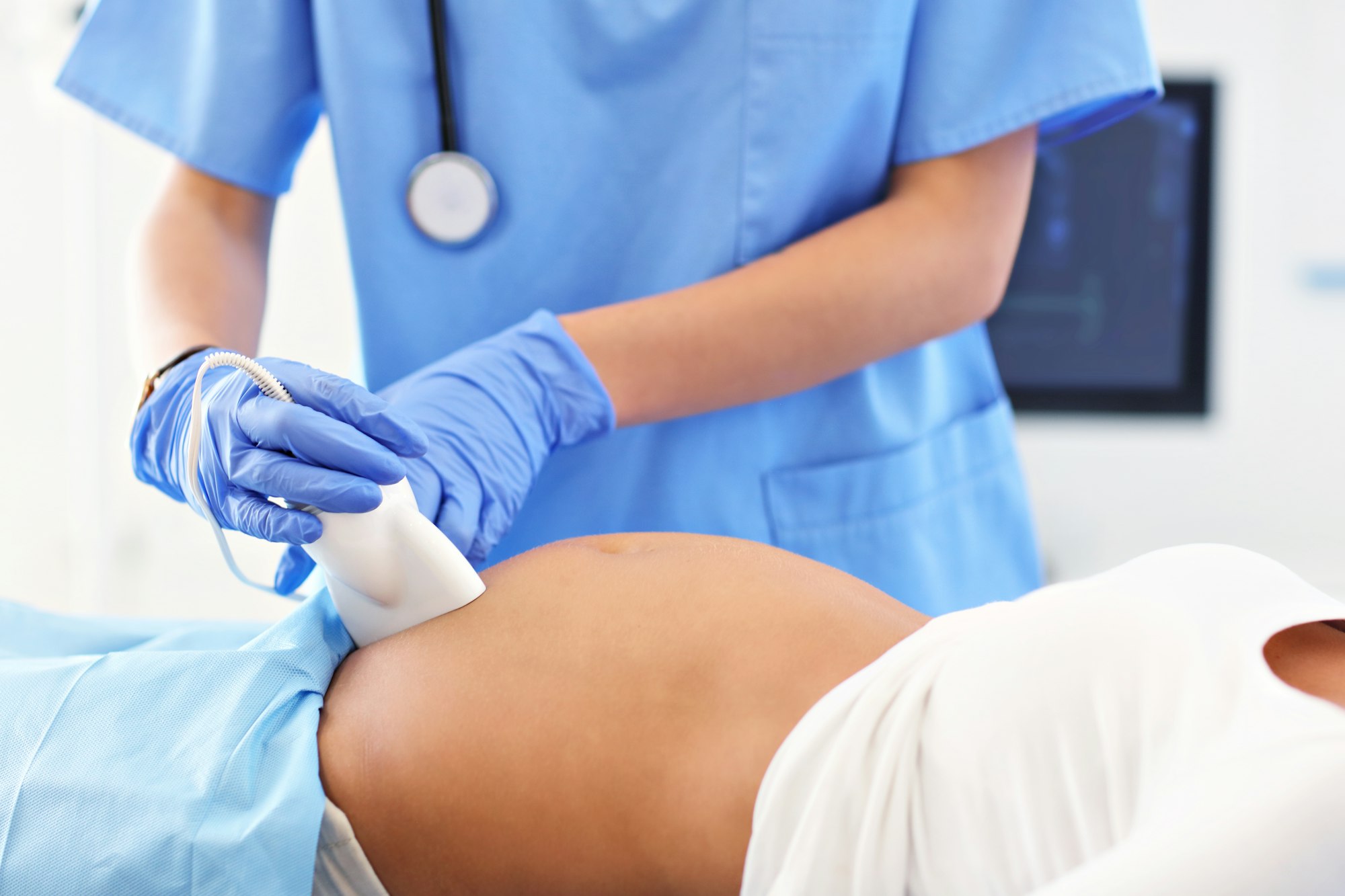 Pregnant woman having ultrasound tests during visit at female doctor's office