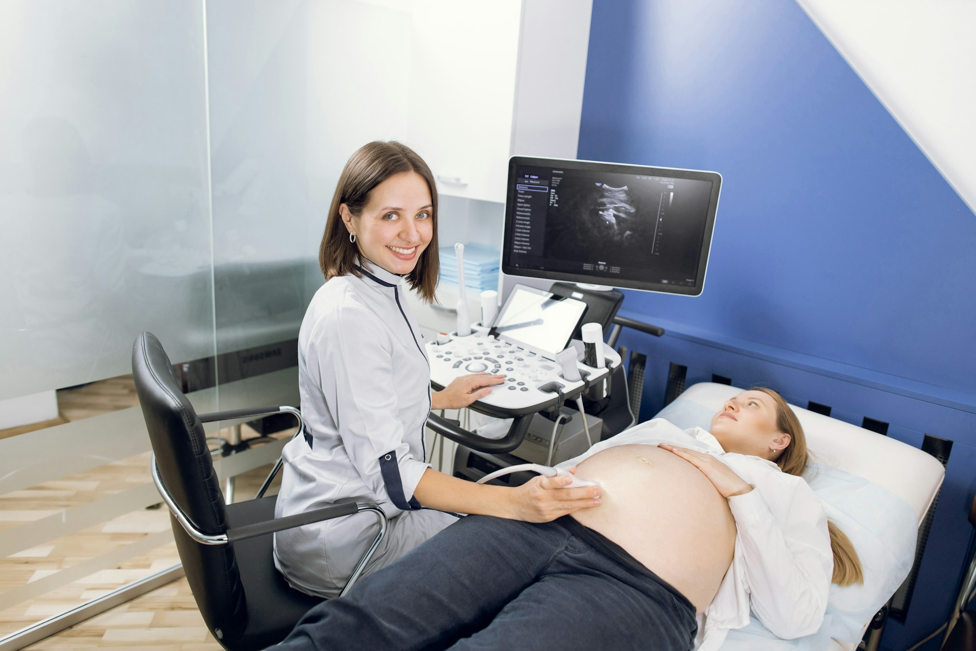 Young attractive gynecologist, checking fetal life with scanner.